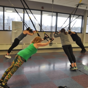 Four individuals in a TRX group exercise class.