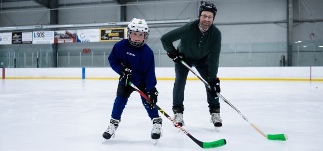 A man and his son playing ice hockey